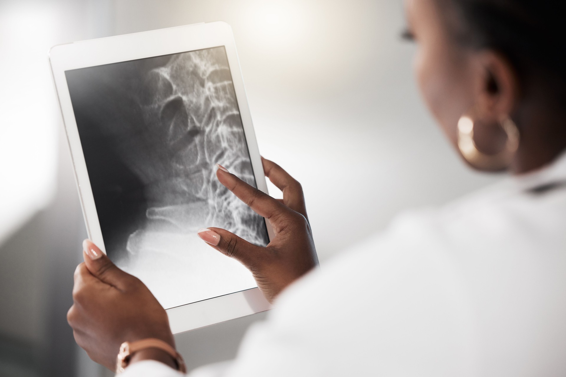 Shot of a doctor analysing an x ray on the screen of a digital tablet